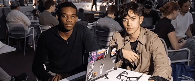 Two founders at a table with laptops and stickers