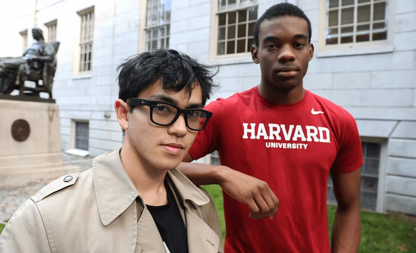 Two students outdoors in glasses, one wearing a Harvard shirt